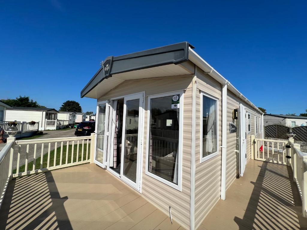 a tiny house with a solarium on a deck at Lets Host Hot Tub Holiday Home with Lake view in Patrington