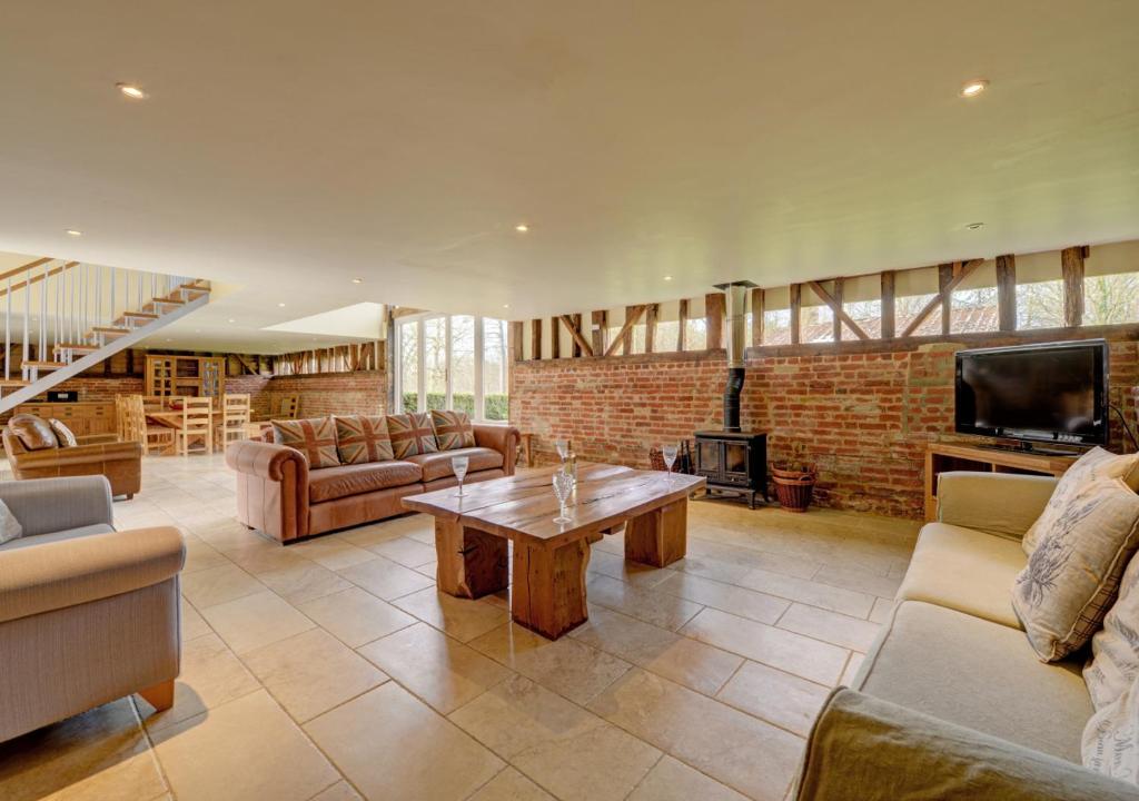 a living room with couches and a table and a fireplace at Vale Farm Barns Sutton in Sutton