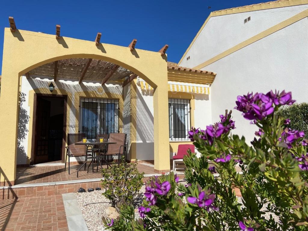 une terrasse d'une maison avec des fleurs violettes dans l'établissement casa limon, à Mazarrón