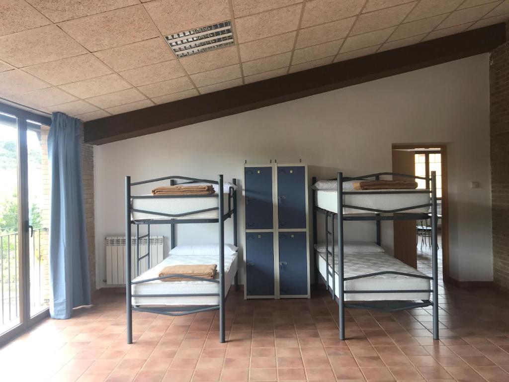 a room with three bunk beds and a window at Albergue de Castillazuelo in Castillazuelo
