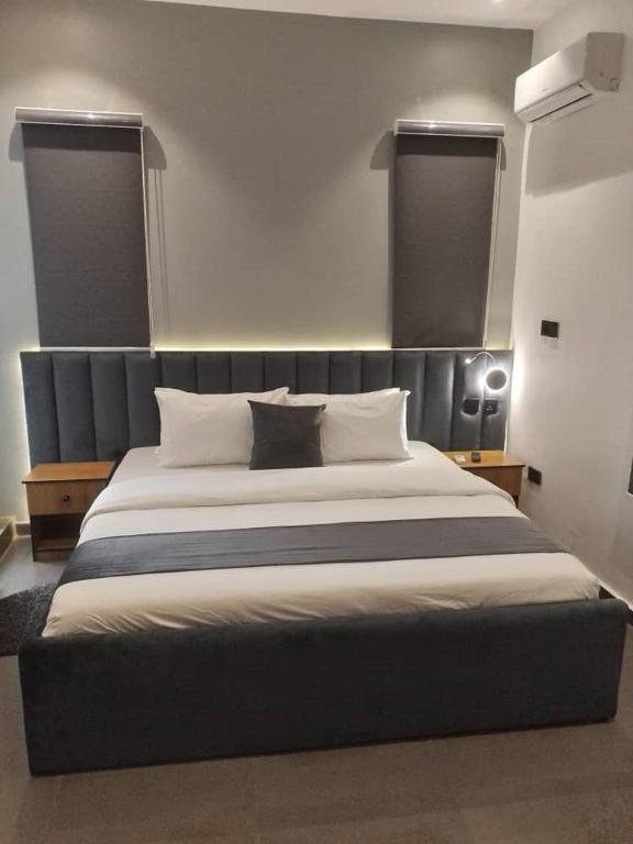 a bedroom with a large bed with two windows at The Grid Residence in Ikeja