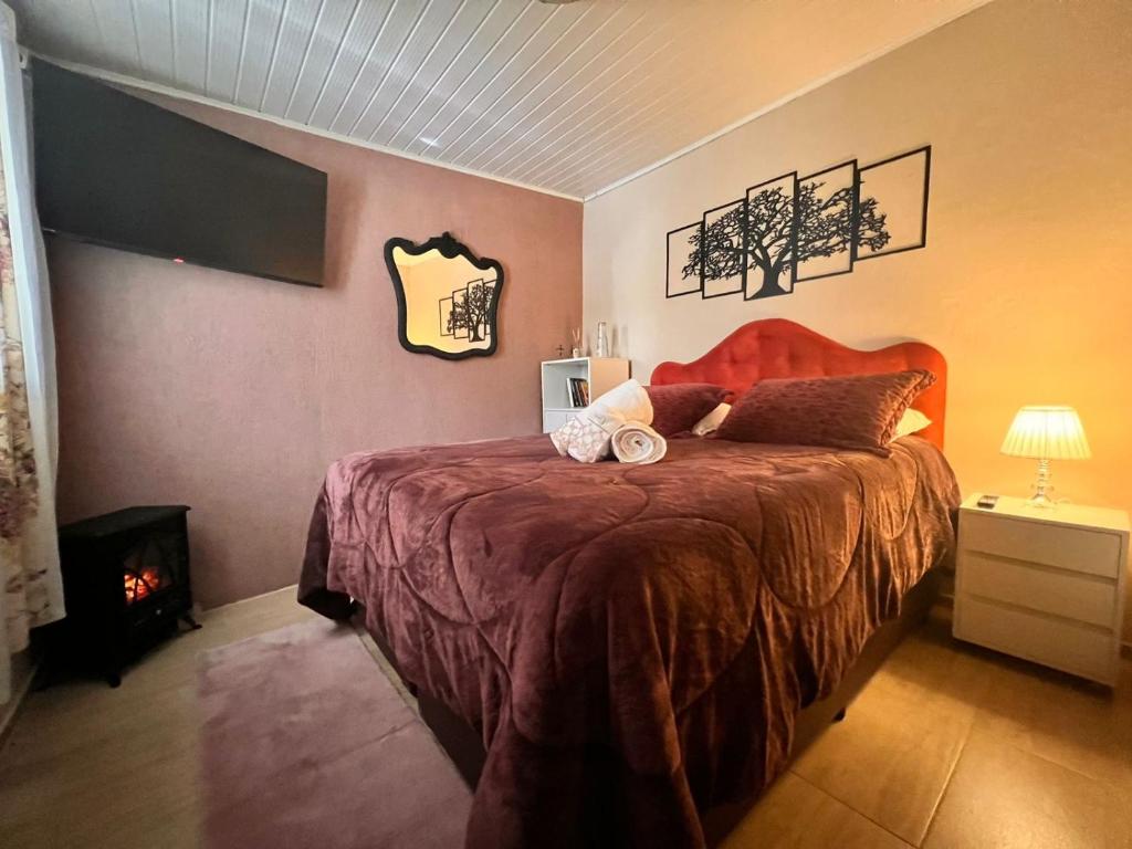 sypialnia z łóżkiem i kominkiem w obiekcie Chalé Completo 5min centrinho w mieście Campos do Jordão