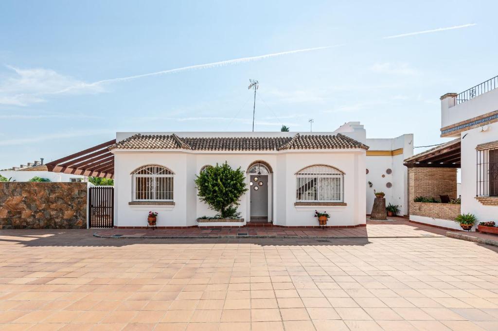 a white house with a brick driveway at Chalet Fuente1 piscina común famila in Conil de la Frontera