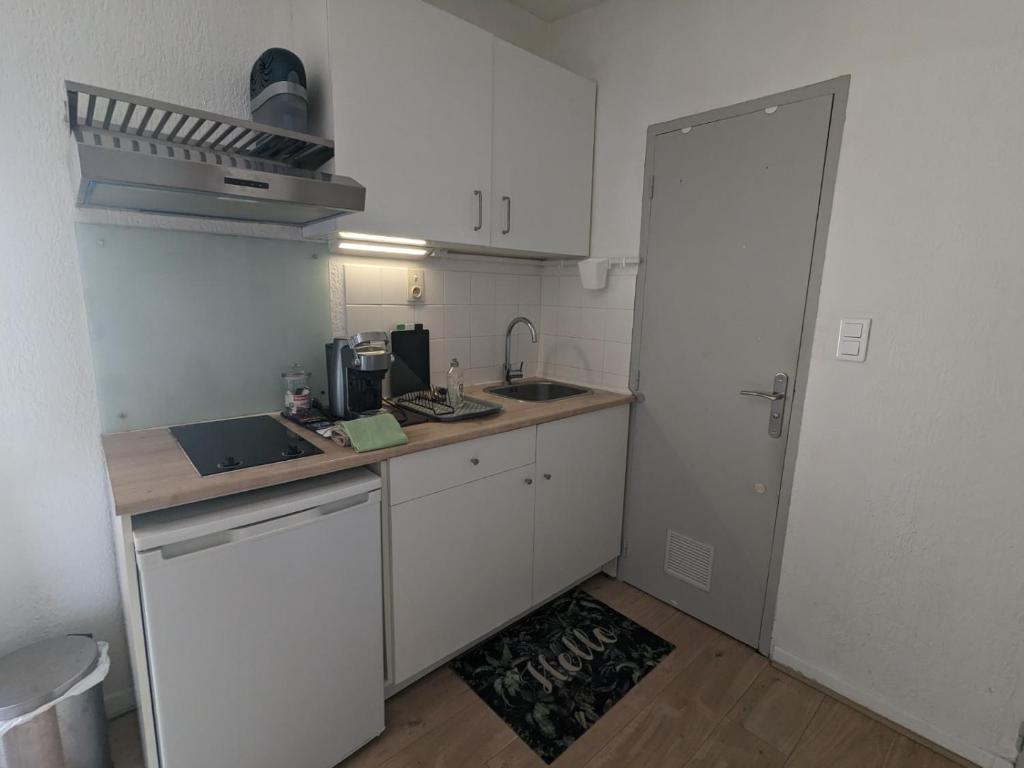 a small kitchen with white cabinets and a sink at STUDIO avec PARKING TOUT A PIED et CALME in Bandol