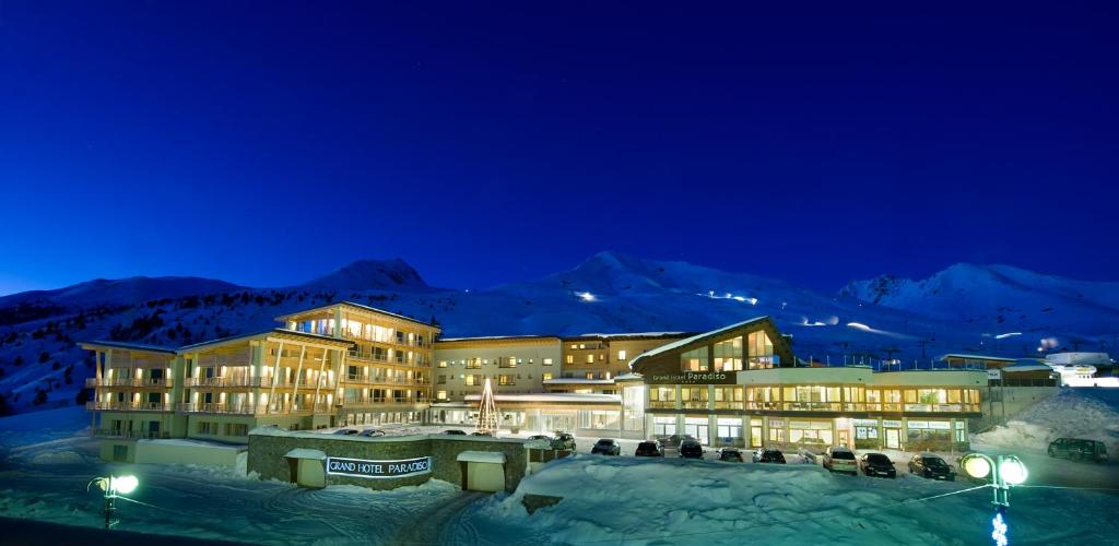 a large building in the snow at night at Grand Hotel Paradiso in Passo del Tonale