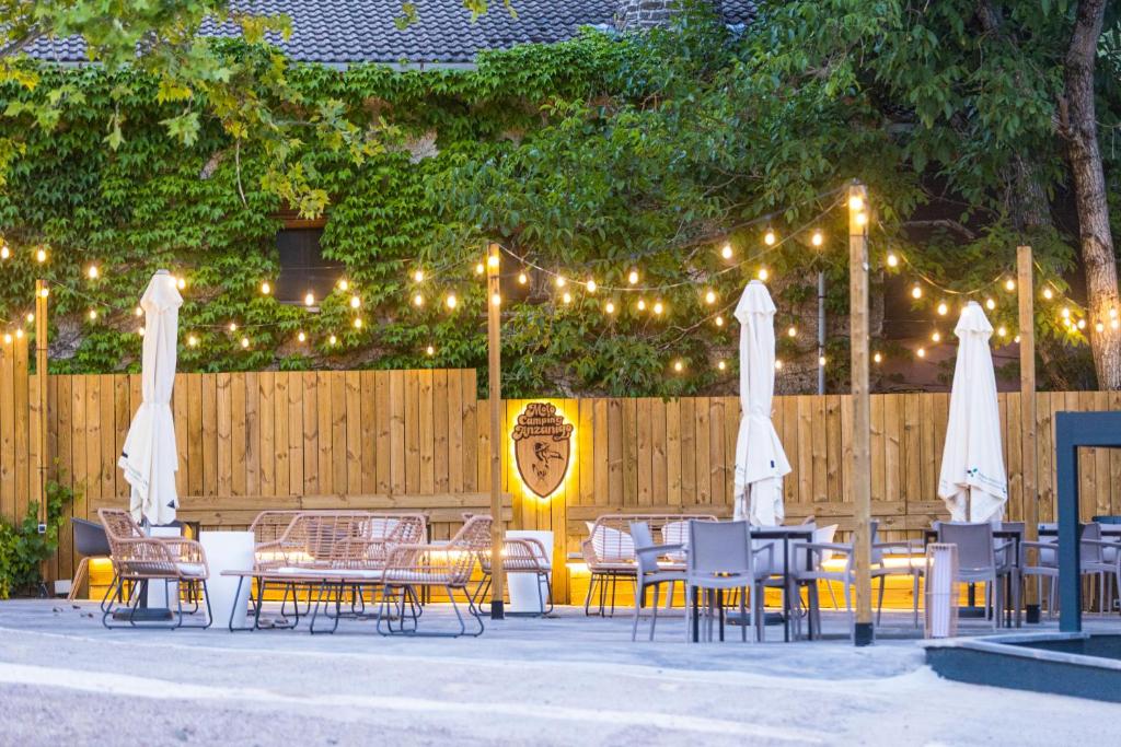 a patio with tables and chairs with lights and a fence at Camping Anzánigo in Anzánigo