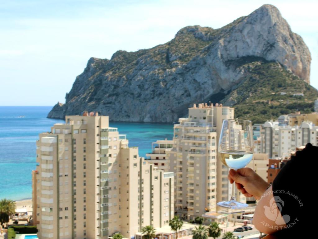 a person holding a wine glass in front of a city at Flamenco Ambar Luxury Apartment 15 Planta in Calpe