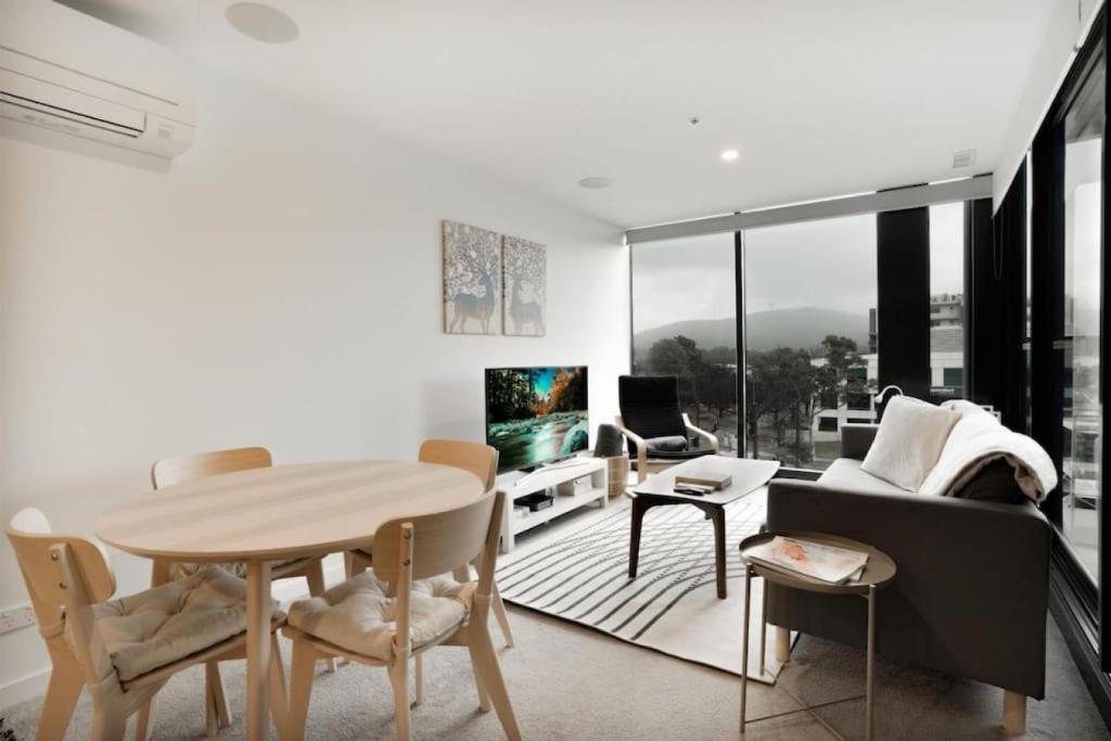 a white living room with a table and a couch at Mountain views at Midnight in the heart of Canberra in Canberra