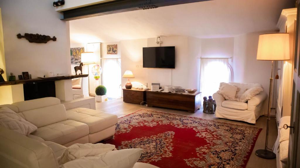 sala de estar con 2 sillas blancas y TV en La Finestra en Bolonia