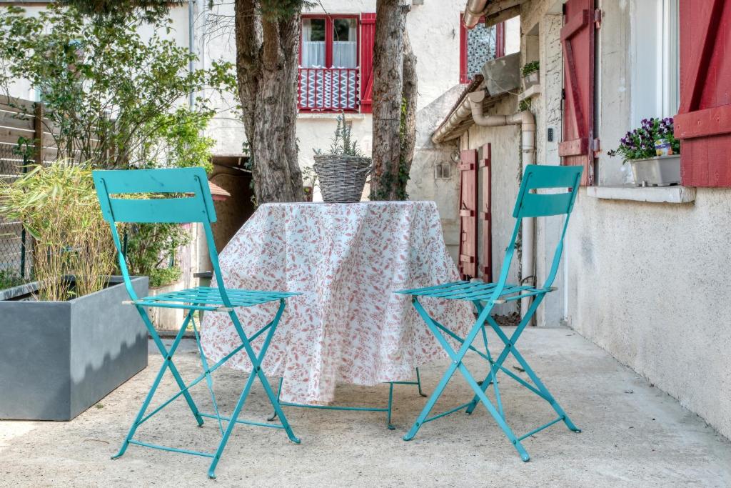 two blue chairs and a table with a table cloth at Cottage Au Coin du Feu in Rambouillet