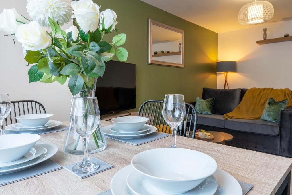 a dining room table with a vase of white flowers at Stylish 2 bedroom, 2 bathroom with Sky TV, Free Parking and WiFi By HP Accommodation in Milton Keynes