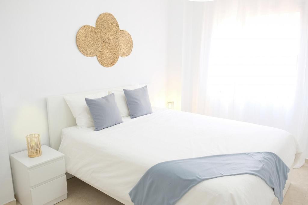 een witte slaapkamer met een groot wit bed met blauwe kussens bij EDEN RENTALS Caletillas Peace in Candelaria