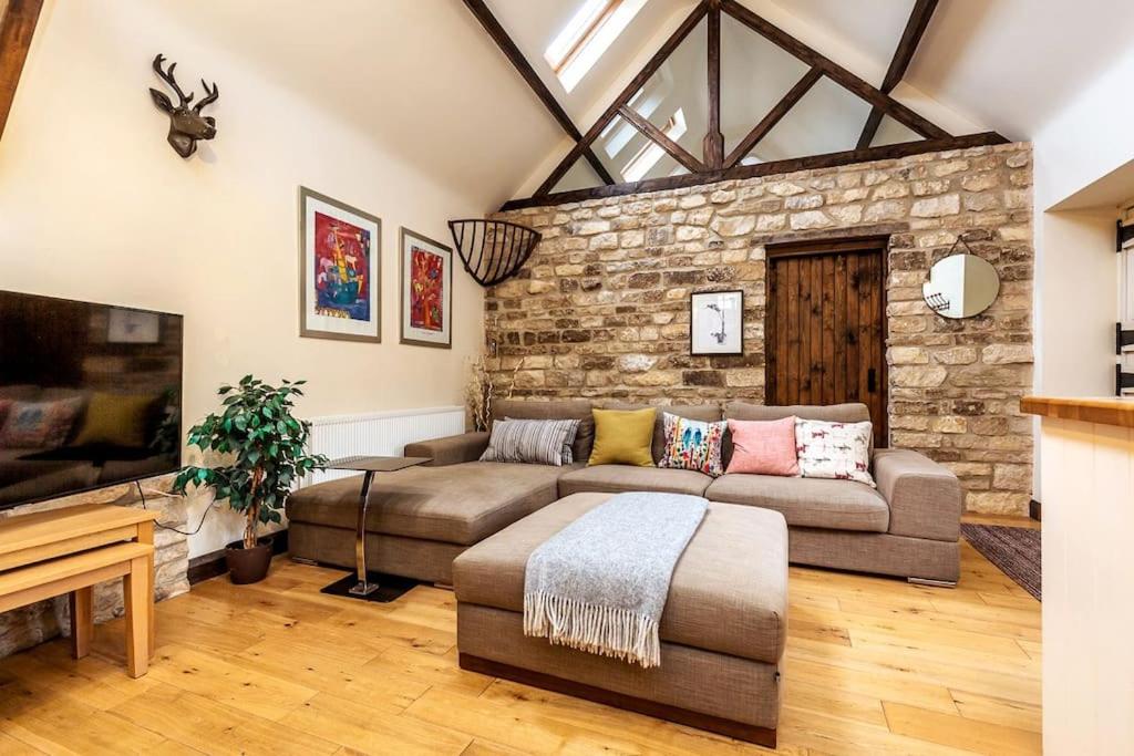 uma sala de estar com um sofá e uma parede de pedra em The Stocks Barn em Wellingore