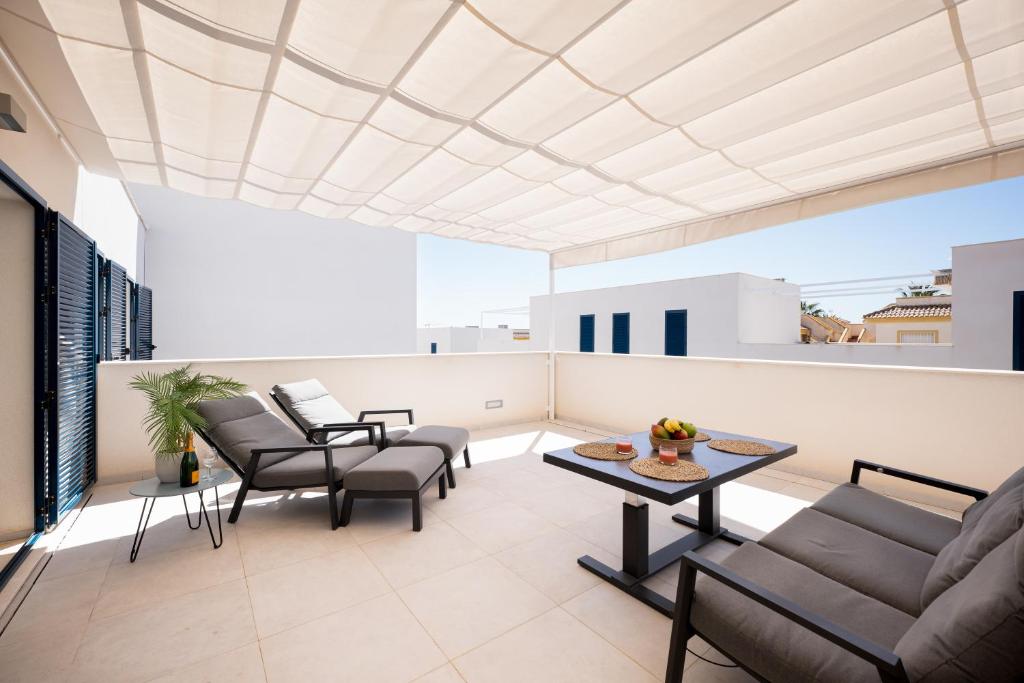 ein Wohnzimmer mit Stühlen und einem Tisch auf dem Balkon in der Unterkunft Turquesa del Mar - Max Beach Golf - Large Sunny Terrace Apartment in Playa Flamenca