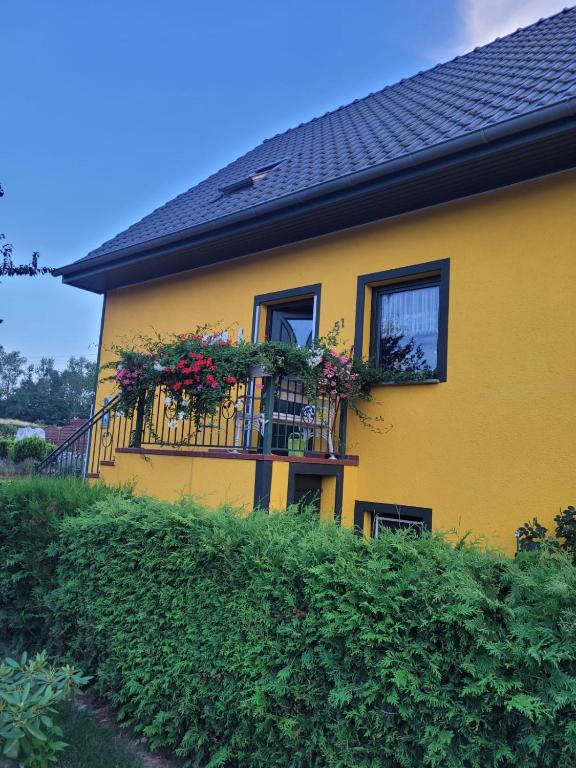 a yellow house with flowers on a balcony at Ferienwohnung Schmidt in Neu Sallenthin
