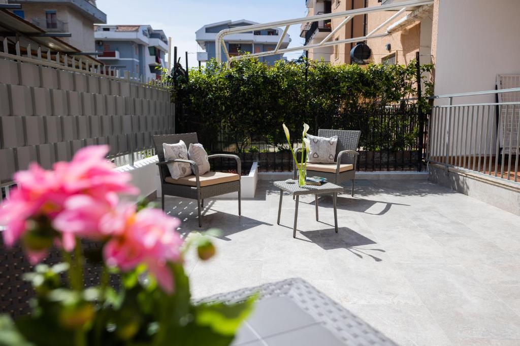 2 chaises et une table sur une terrasse ornée de fleurs roses dans l'établissement Gilda’s Home, à Scalea