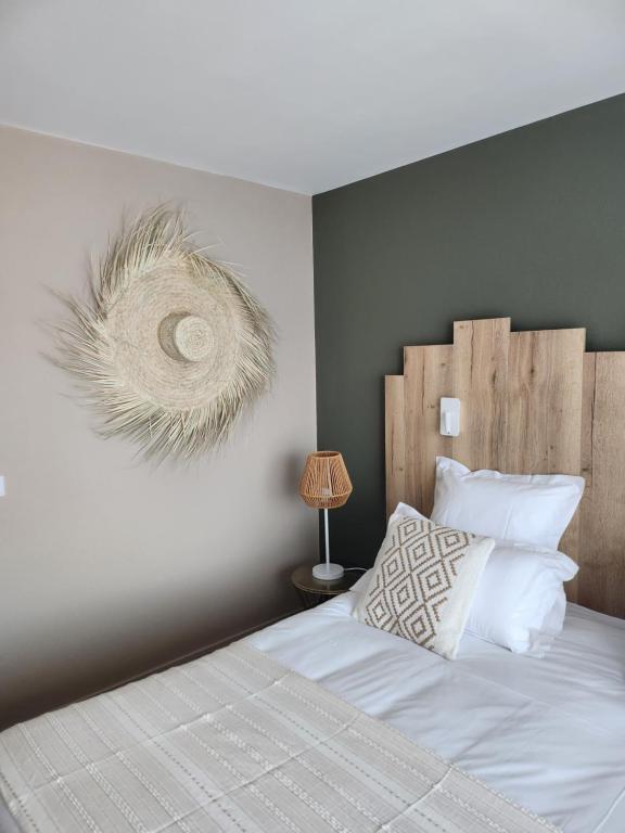 a bedroom with a white bed with a wooden headboard at Hôtel Restaurant BO &amp; MIA in La Baule