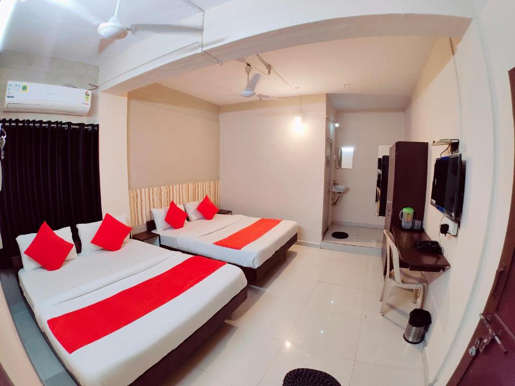 Cette chambre d'hôtel comprend 2 lits avec des oreillers rouges. dans l'établissement Hotel Nawanagar Residency, à Jamnagar