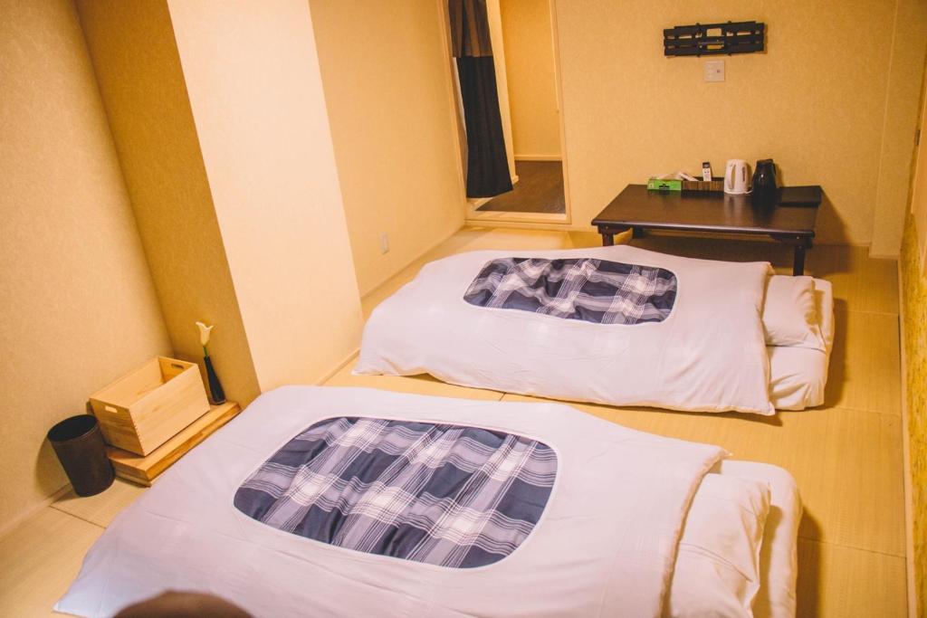 two beds in a small room with a table at WASEIDOU ZEN - Vacation STAY 19522v in Kobe