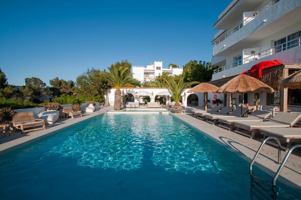 una piscina con sillas y un edificio en Apartamentos Sunset Oasis Ibiza - Only Adults, en Bahía de San Antonio
