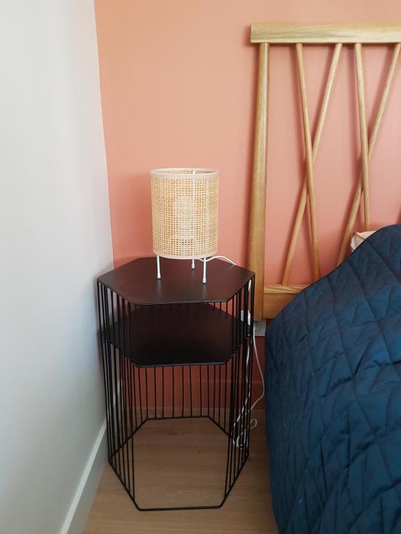 a black end table with a lamp next to a bed at Au ptit Manoir in Montbert
