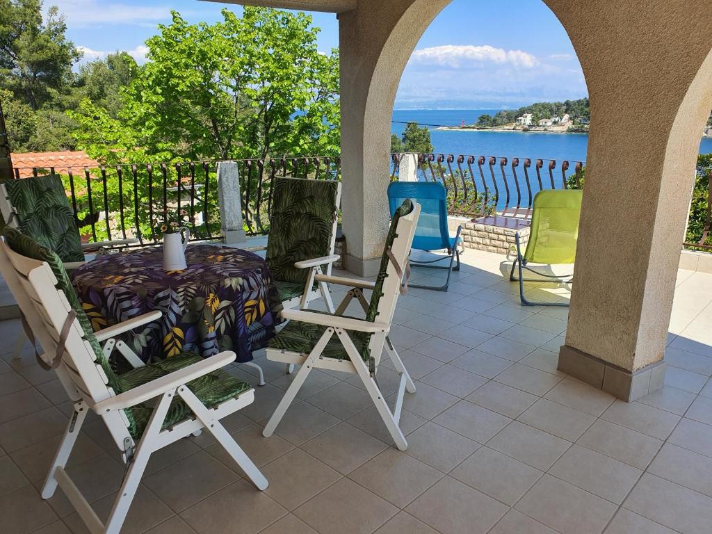 einen Tisch und Stühle auf einer Terrasse mit Blick auf das Wasser in der Unterkunft Mendula Apartment in Rogač