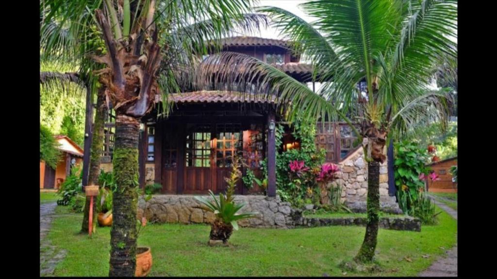 a house with palm trees in front of it at Chalés internacional l in Paraty