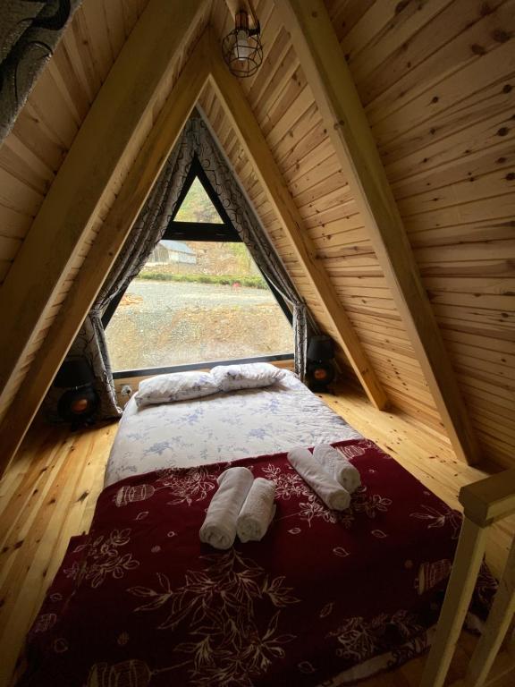 ein Schlafzimmer mit einem Bett im Dachgeschoss mit einem Fenster in der Unterkunft Lelvani Suite Bungalow in Rize