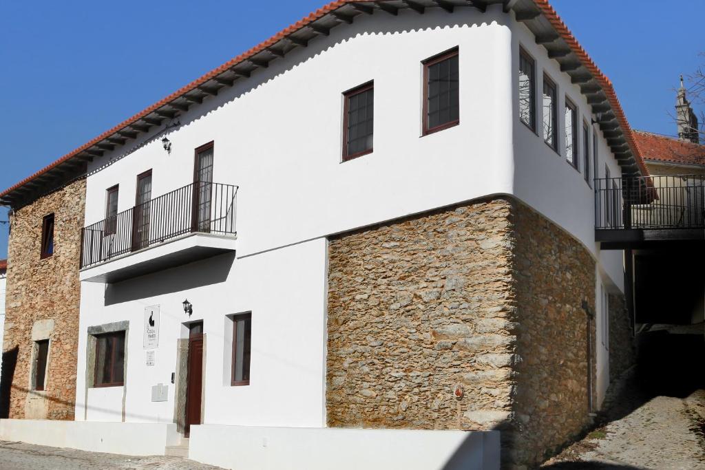 a white building with a stone wall and balcony at Casa do Médico in Carção