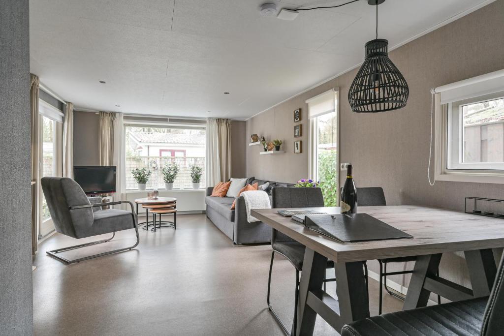 een woonkamer met een bank en een tafel bij Ruime Luxe Chalet midden in de Veluwe. in Hoenderloo