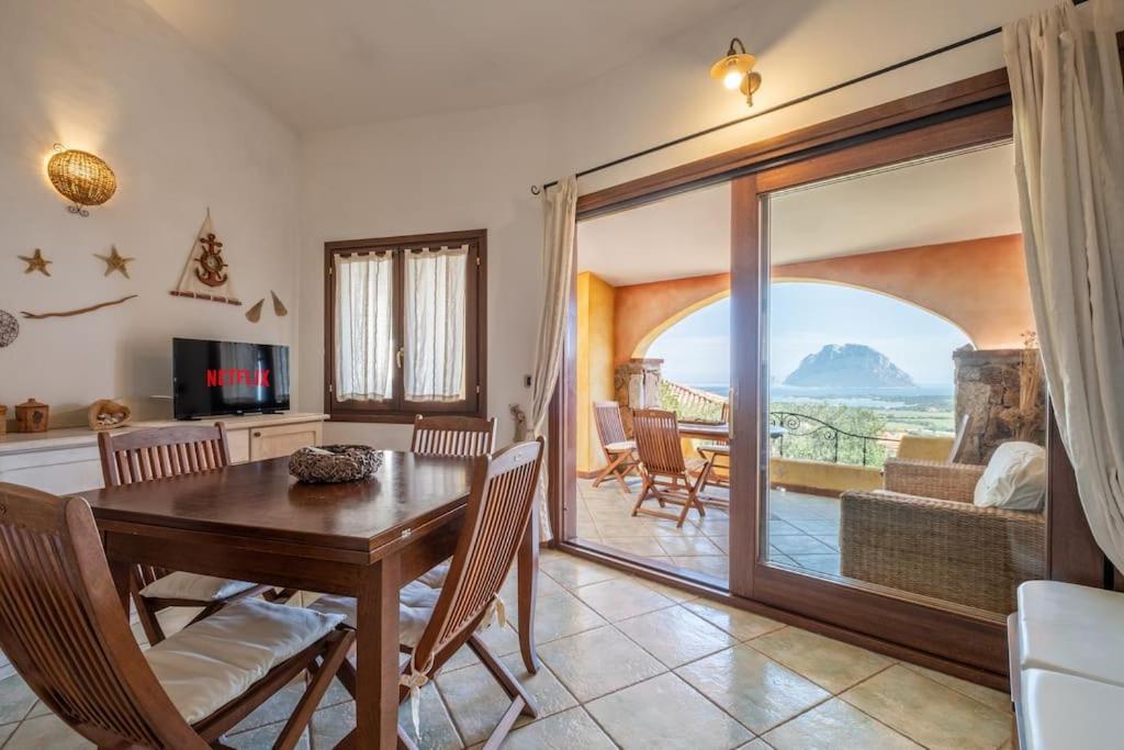 a dining room with a table and a balcony at [FREE Parking] Villa - stunning view of Tavolara in Porto San Paolo