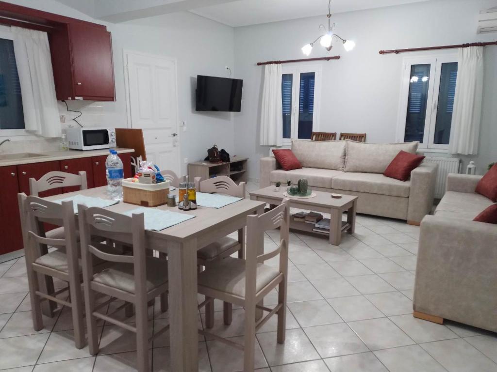 Lefakis Aegean Breeze Apartment في Órmos: مطبخ وغرفة معيشة مع طاولة وكراسي
