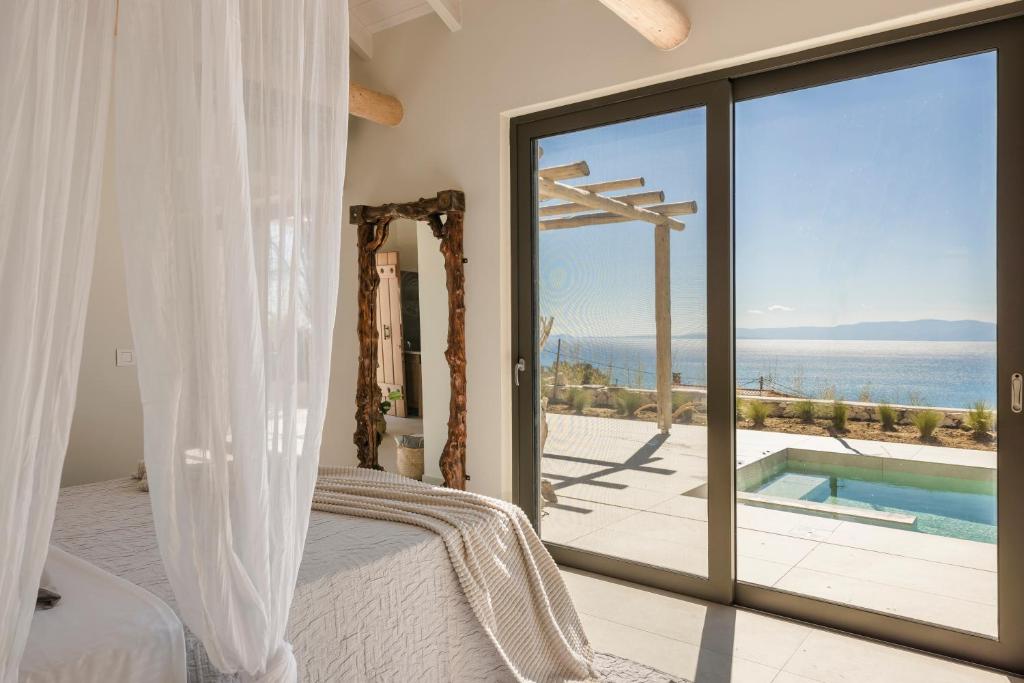 a bedroom with a bed and a view of the ocean at Spathes Suites Kefalonia - Luxury Suites in Ratzaklíon