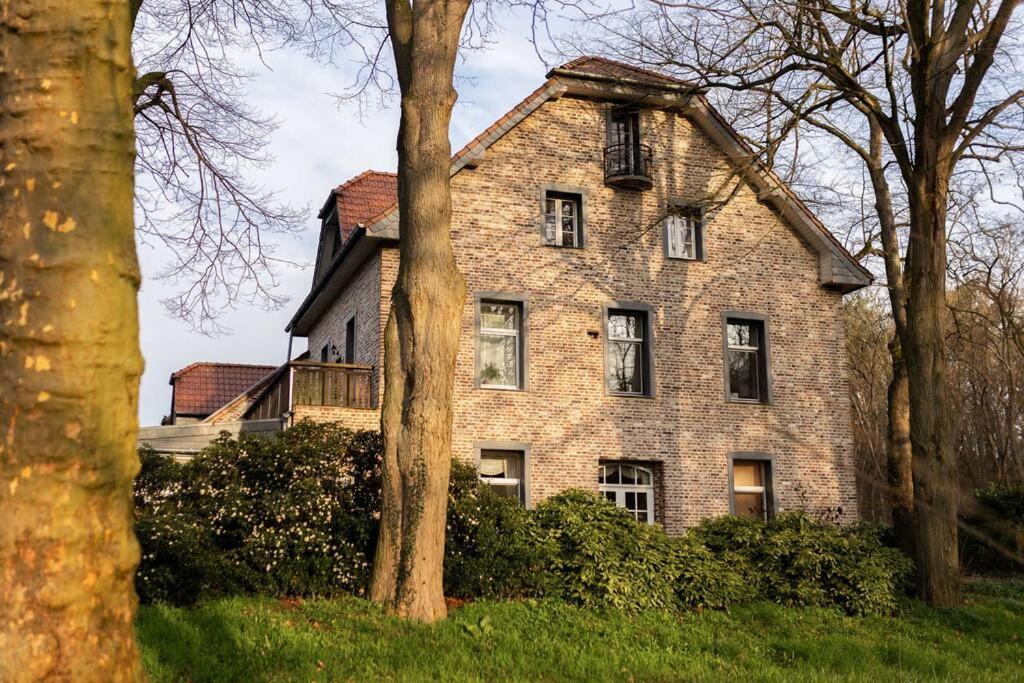 uma velha casa de tijolos com árvores em frente em Ferienhof in Weeze-Wemb em Weeze