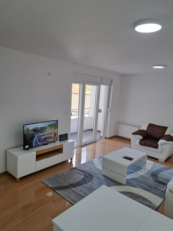 - un salon blanc avec une télévision et un canapé dans l'établissement Apartmani Swiss LUX Pozarevac, à Požarevac