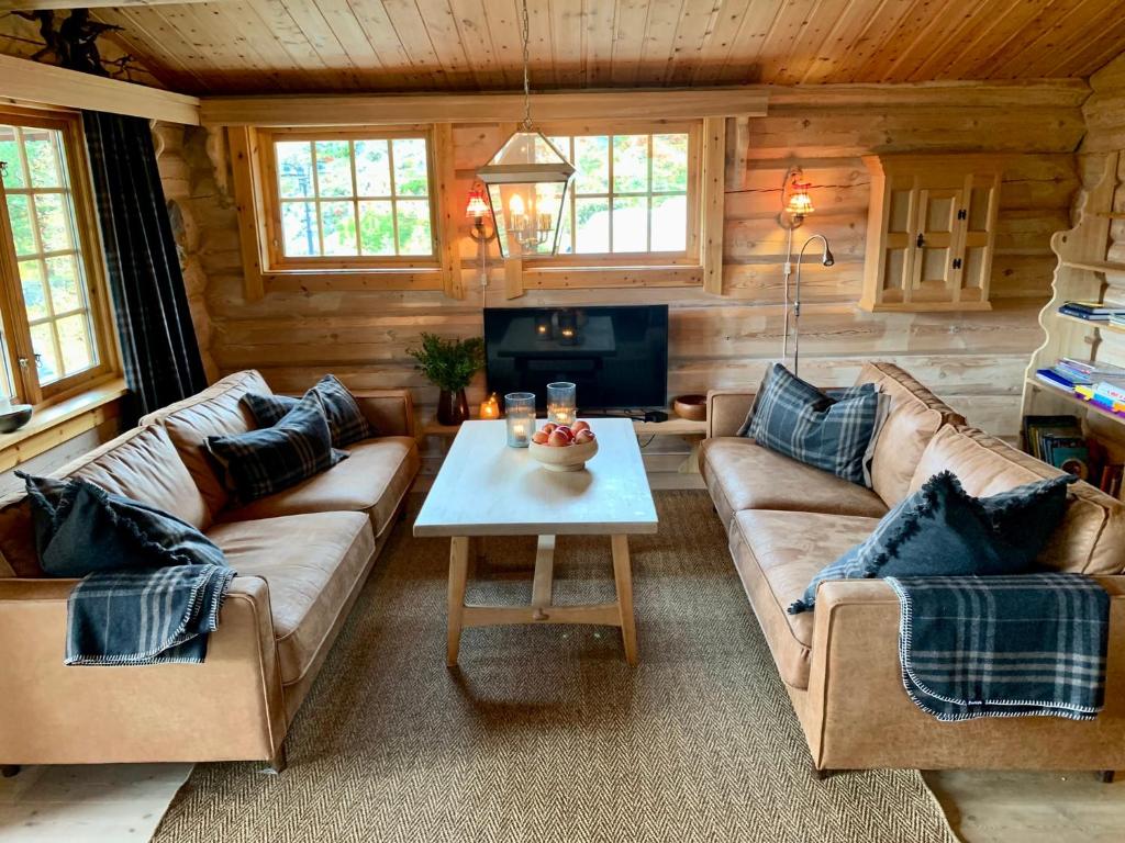 ein Wohnzimmer mit Sofas und einem Tisch in einer Hütte in der Unterkunft Timber Lodge in Uvdal Skisenter VIEW/WIFI in Sønstebø