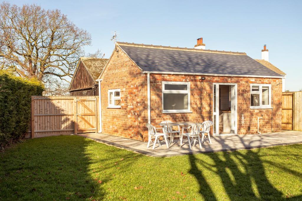 a brick house with a table and chairs in a yard at Willow Cottage a quaint holiday cottage in Wigtoft Boston Lincolnshire in Boston