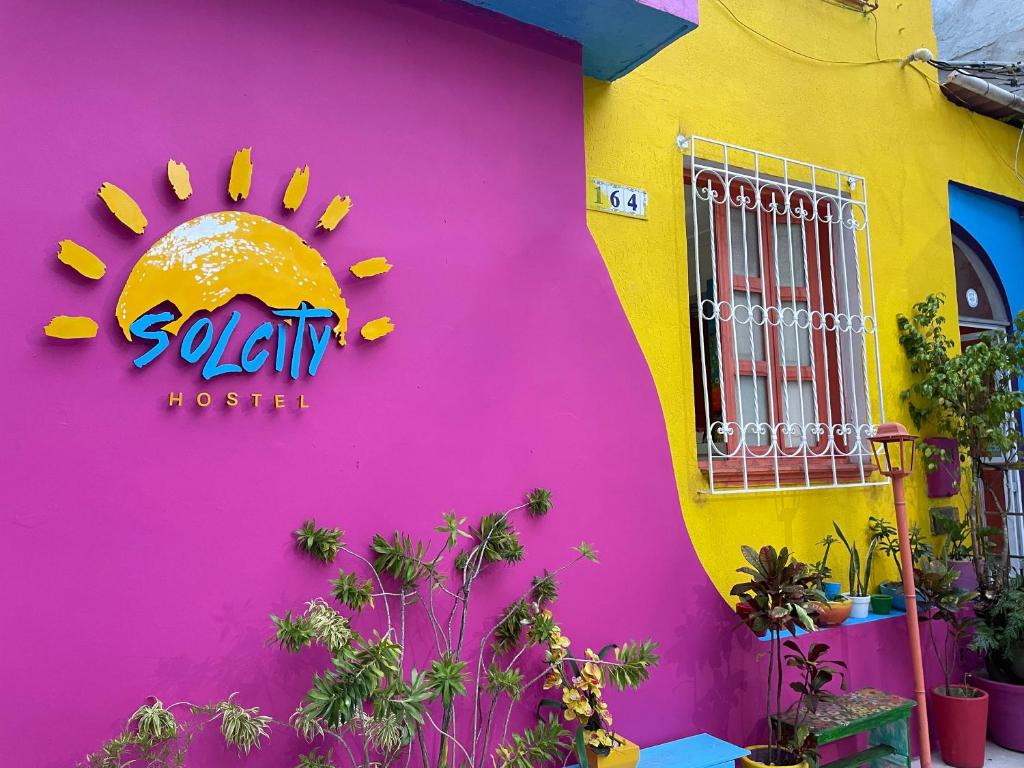 a pink and yellow wall with a sign on it at Solcity Hostel in Salvador