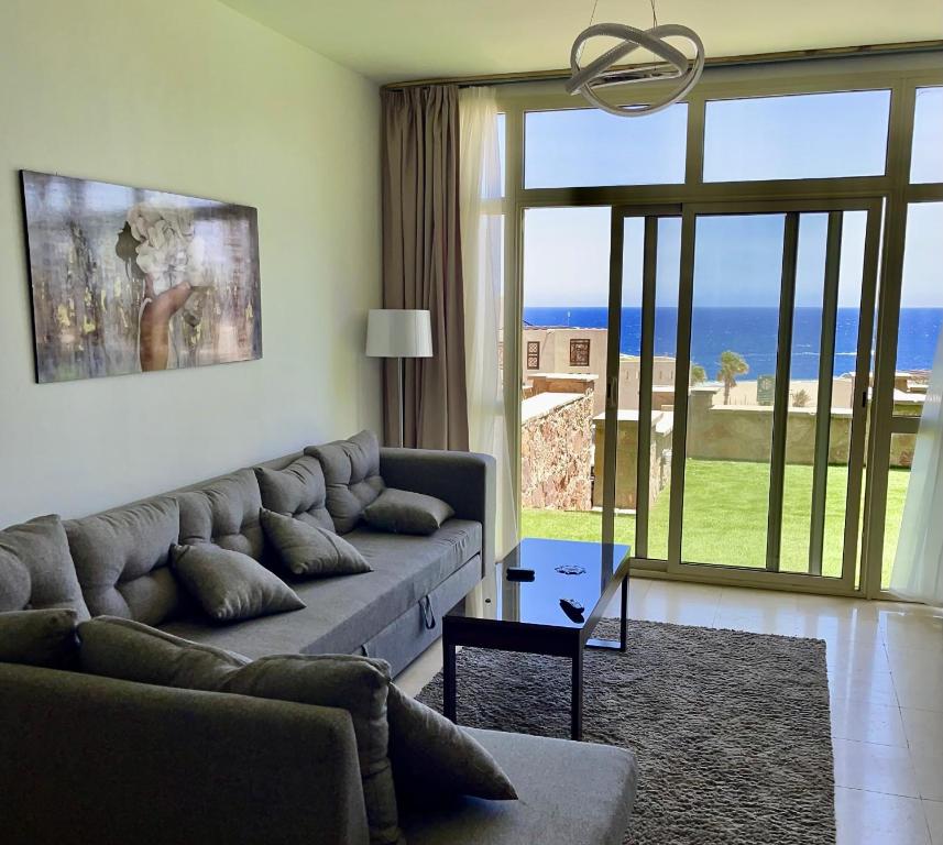uma sala de estar com um sofá e vista para o oceano em Apartment Azzura Sahl Hasheesh with private garden em Hurghada