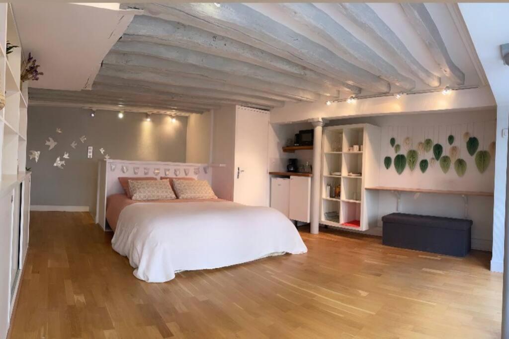 une chambre avec un lit blanc et un parquet dans l'établissement Beau studio Gare de Lyon, à Paris