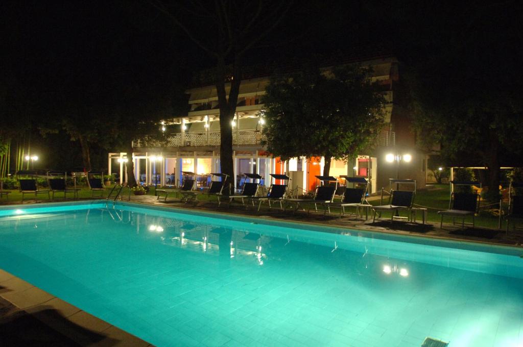 una piscina con sedie e un edificio di notte di Hotel Hermitage a Marina di Massa