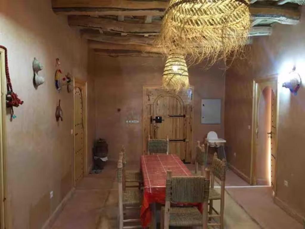 een eetkamer met een tafel en stoelen en een kroonluchter bij Berberbayt lodge maison privé in Tinerhir