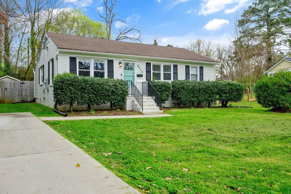 a white house with a blue door at Cozy 3 Bedroom Cottage with Huge Fenced-In Yard in Raleigh