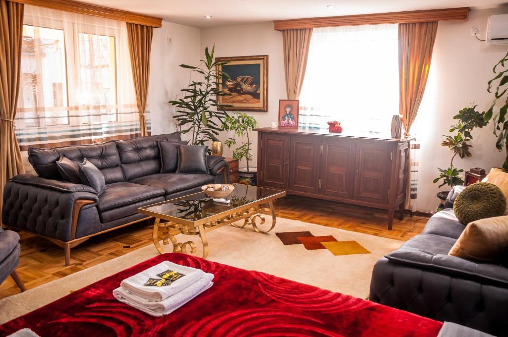 a living room with leather couches and a table at Petrov konak - apartman Aleksandra 