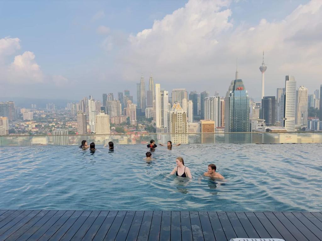 un grupo de personas en una piscina infinita con vistas al perfil urbano en Regalia Modern Studio, en Kuala Lumpur