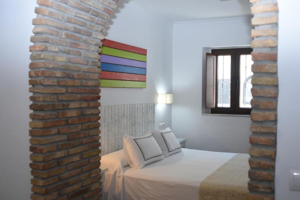 a room with a bed and a brick wall at Hostal Doña Lola Marina in Zahara de los Atunes