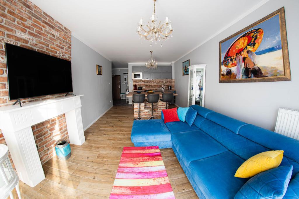 a living room with a blue couch and a fireplace at Apartament Leśna in Pobierowo