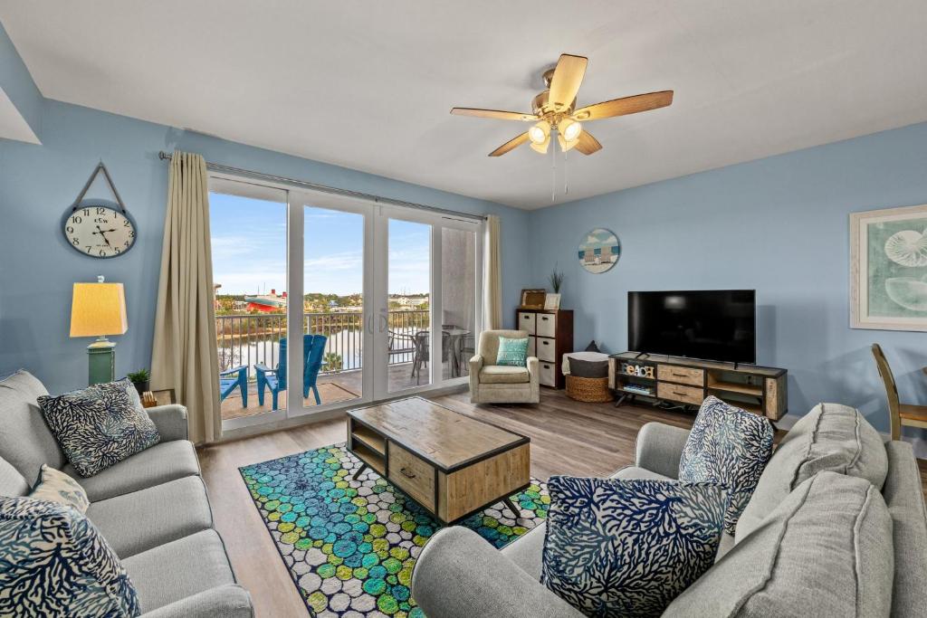 a living room with a couch and a tv at White Sandy Beaches, Sunsets & Seashells at Laketown Wharf #402 by Nautical Properties in Panama City Beach