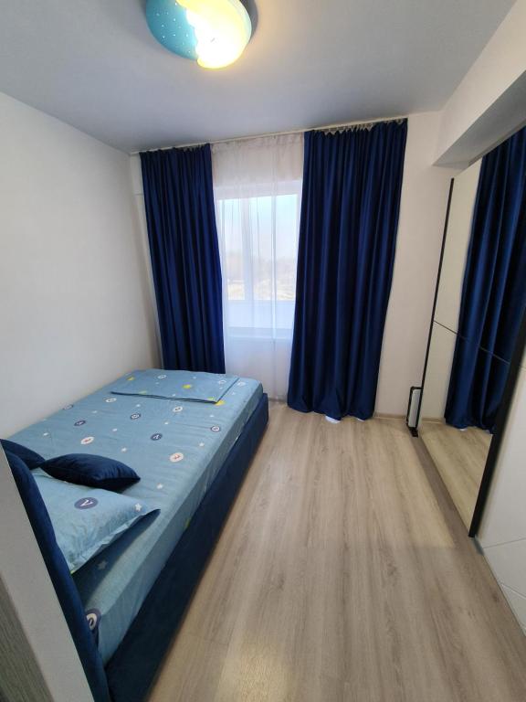 a bedroom with a bed and a window with blue curtains at Micul Arman in Techirghiol