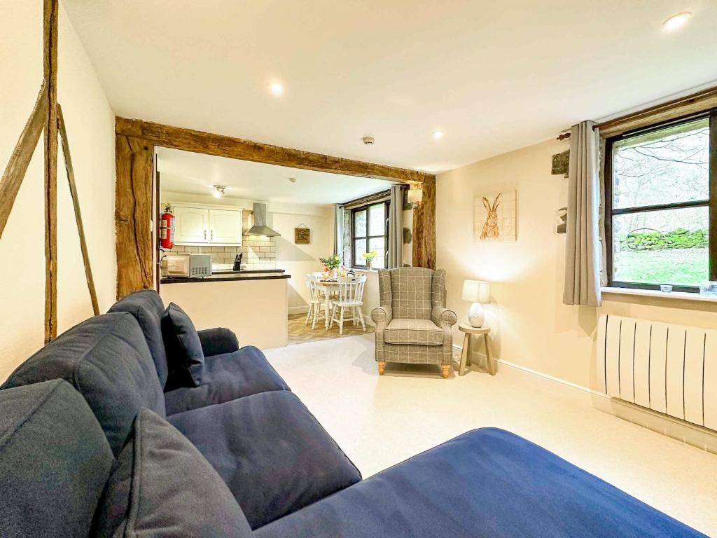 uma sala de estar com um sofá azul e uma cozinha em Kite 1 - Uk6549 em Llanfihangel-Bryn-Pabuan